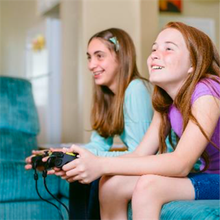 Two tweens playing video games sitting on a couch