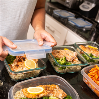 hands putting the lid on a meal prep container with food