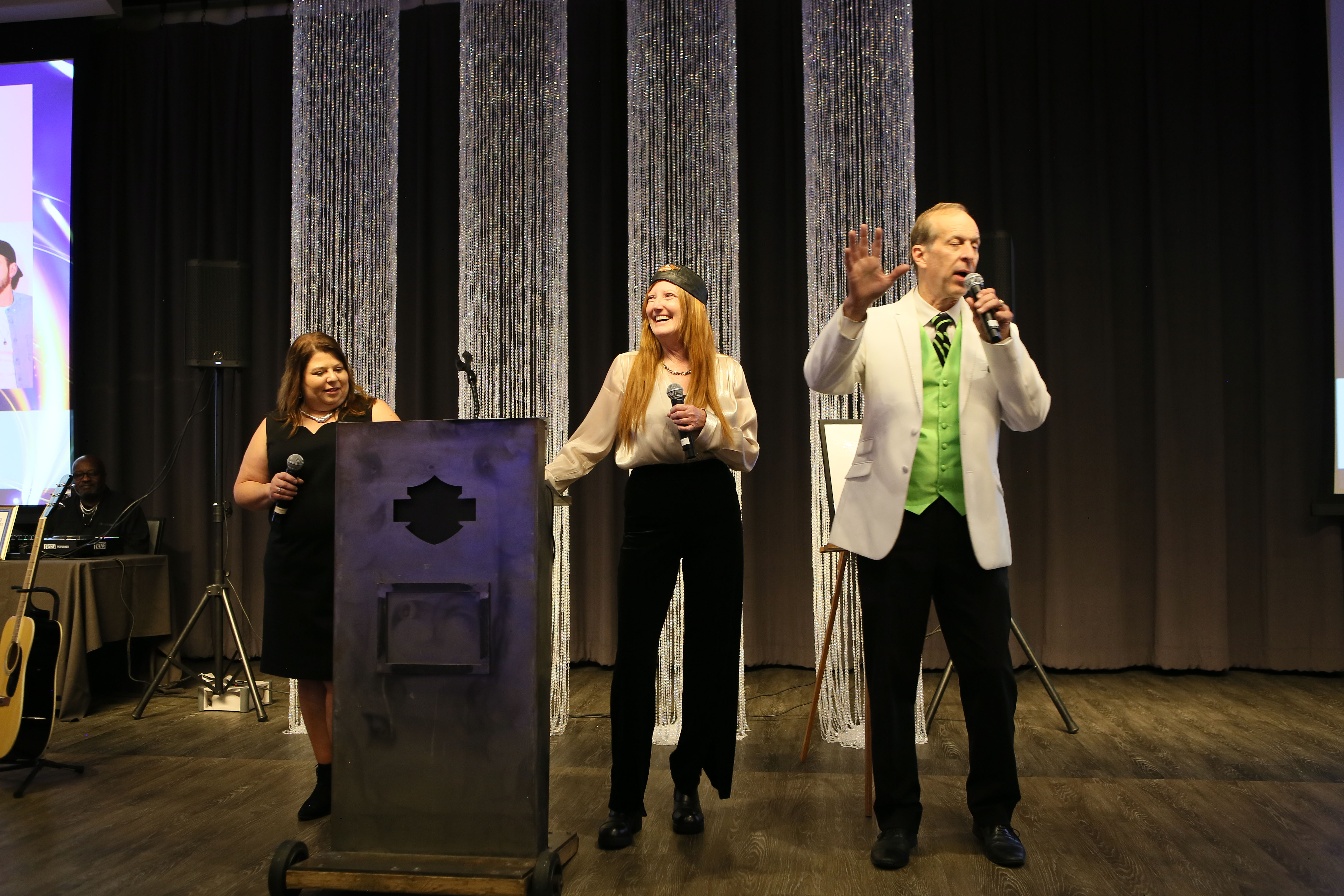 CFO Wendy Huot, CEO/President Marci Boucher, and auctioneer Dan Pronley at the podium