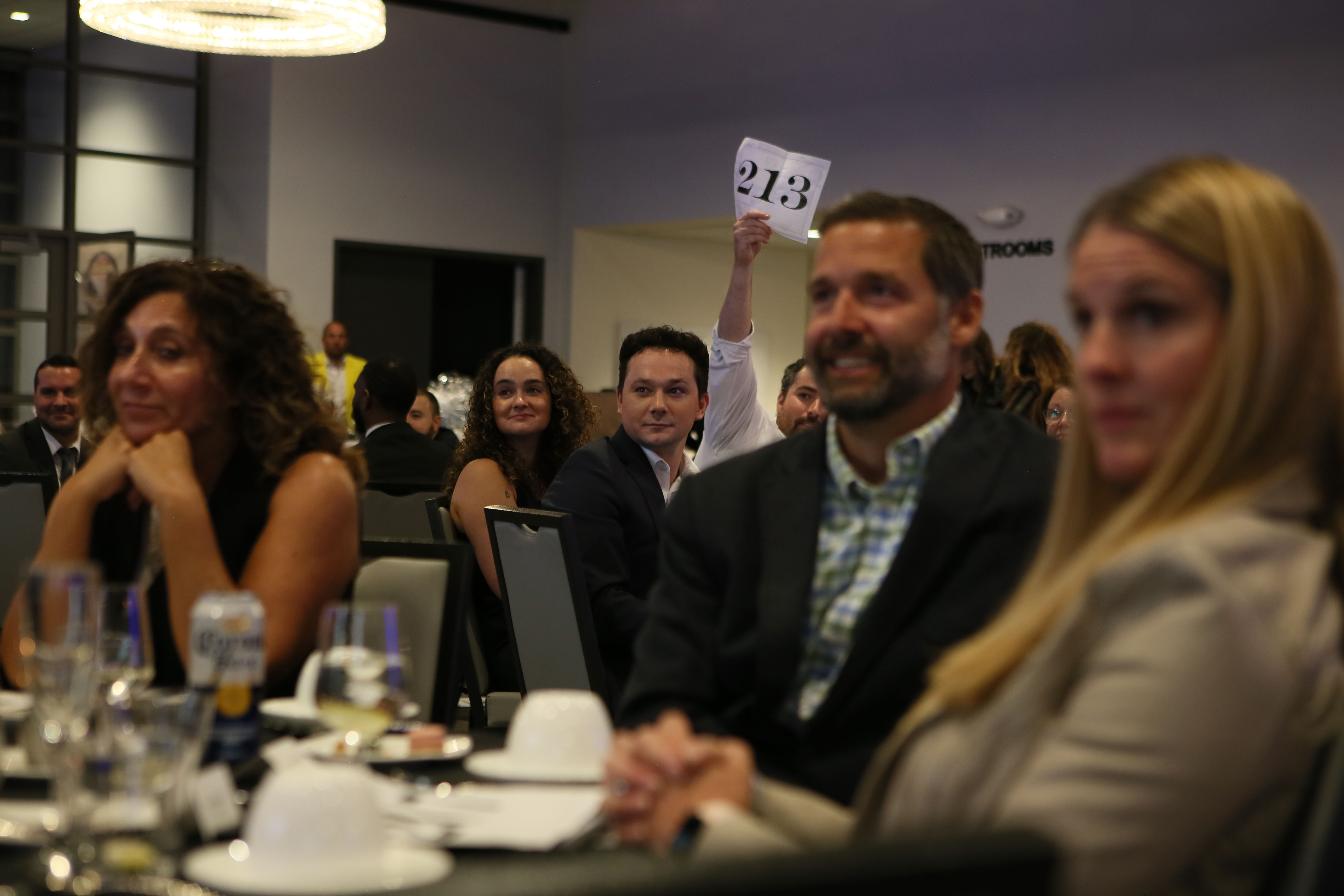 Picture of the crowd with a bidder holding up their bidder number during the live auction