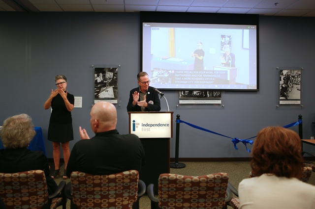 Photo of Tony Snell speaking to event attendees next to an ASL interpreter