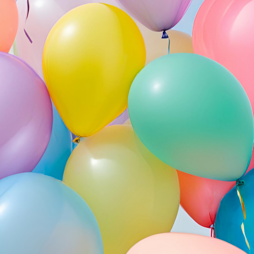 Close-up of colorful balloons in shades of yellow, teal, blue, pink, purple and orange clustered tog