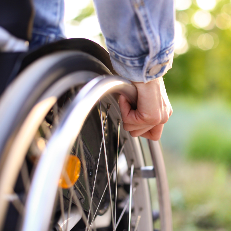 Close-up photo of a person using a manual wheelchair outdoors.