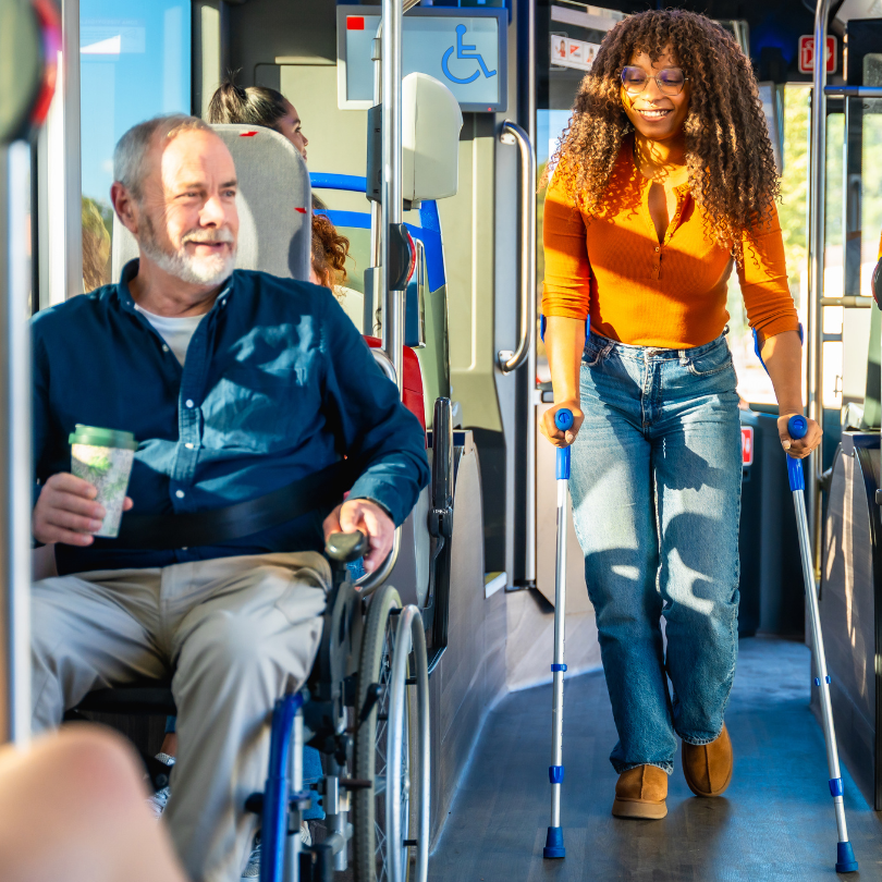 Interior of a city bus showing accessible transit in use. A man sits in a wheelchair in the priority