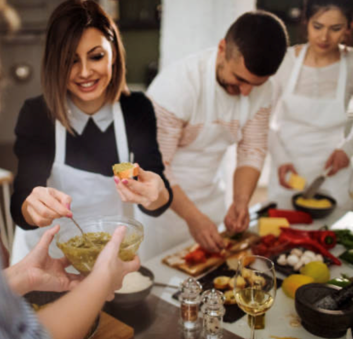 A woman smiling in a cooking class surrounded by other students