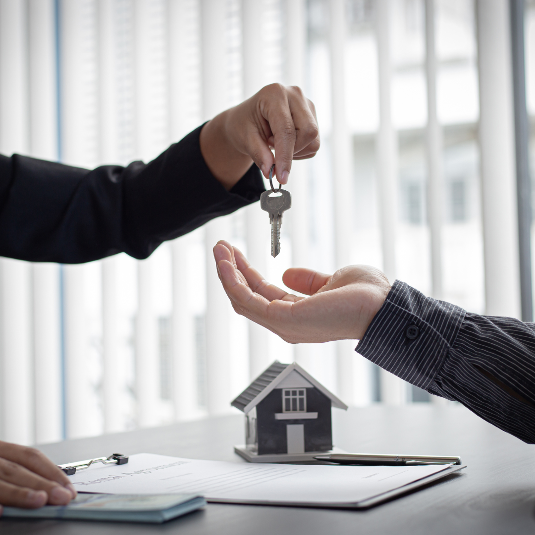photo of a hand passing a set of house keys to another person
