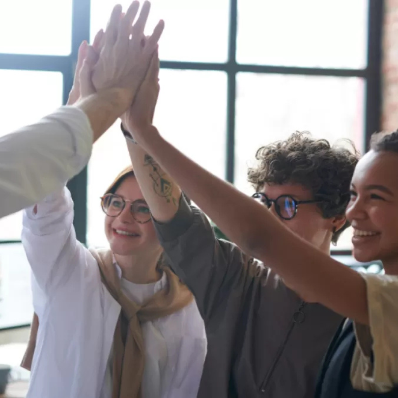 A group of young adults high-fiving each other