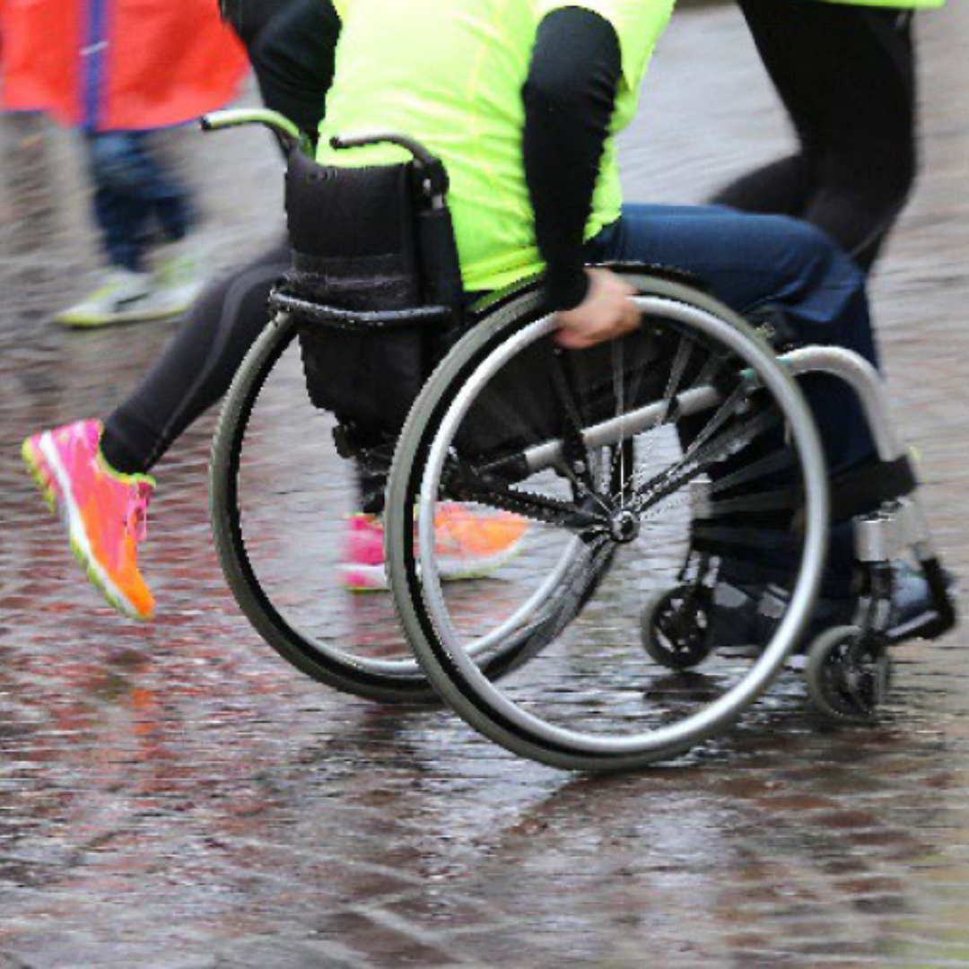 An athlete using a wheelchair participates in a marathon in the rain