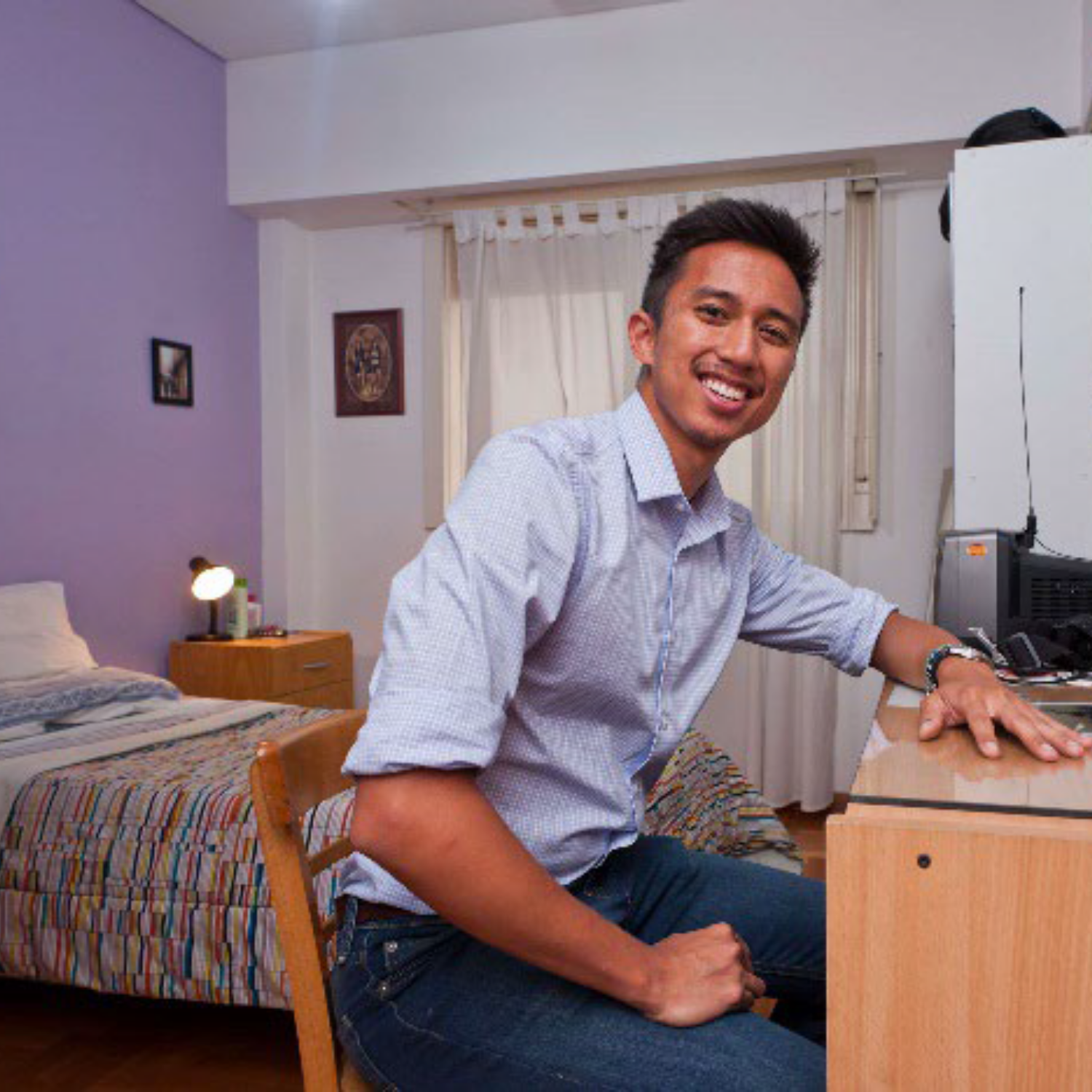 Photo of a young man in a studio apartment seated at a desk