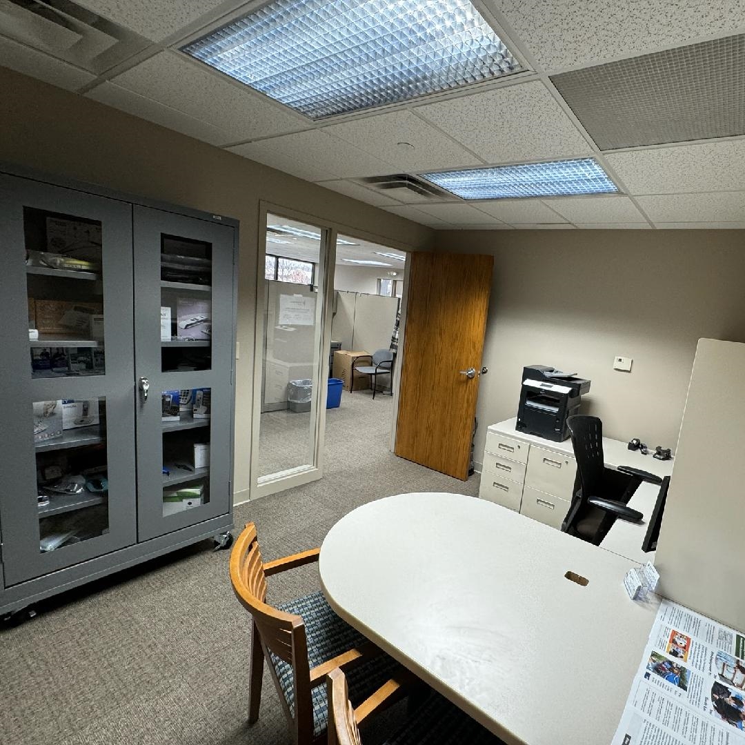 an office with a desk, a chair, and cabinets with an interior window