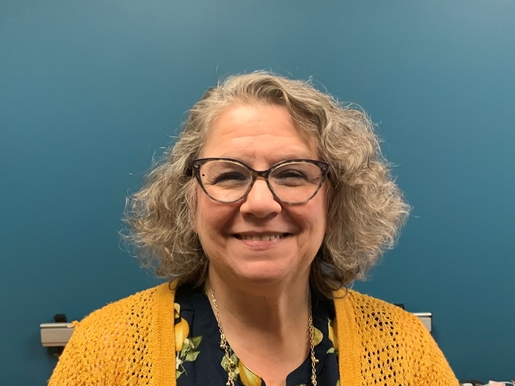 Photo of Rebecca Rabatin wearing glasses in front of a blue wall