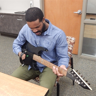 Man with limb difference plays guitar