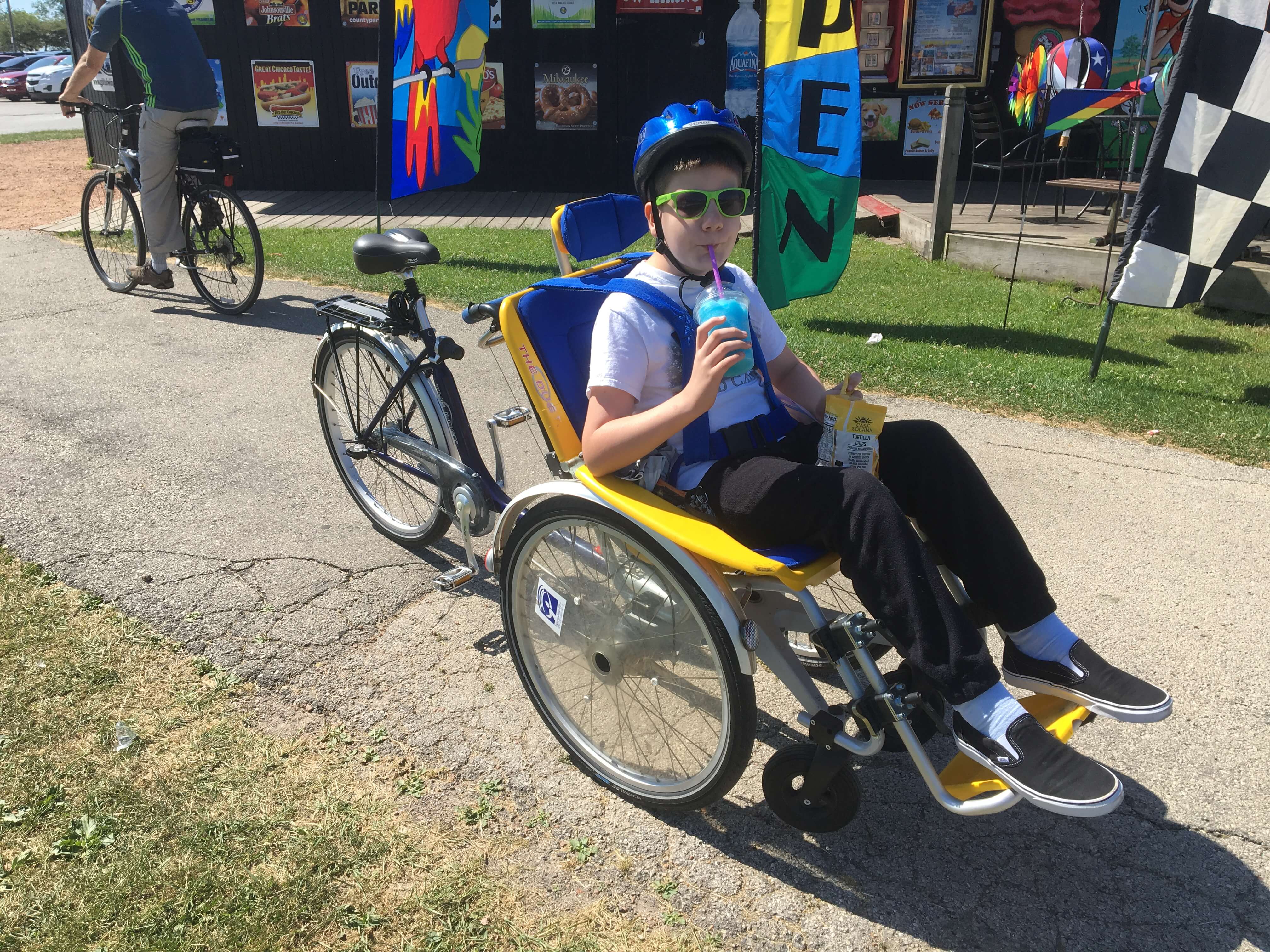 A child wearing sunglasses and a helmet rides a duet bike