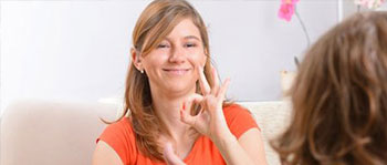 Two women facing each other.  One is using sign language to communicate.