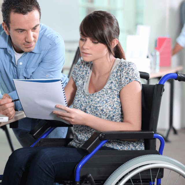 woman in wheelchair discussing a paper document with a man