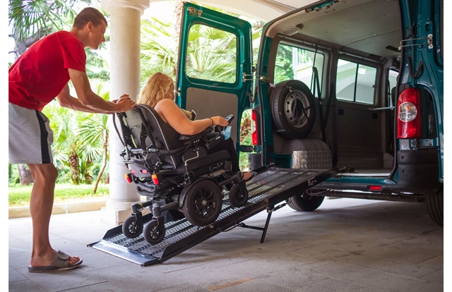 a woman using a wheelchair is pushed up a ramp into a van