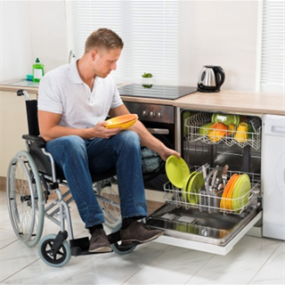 Man puts a plate in a dishwasher while sitting in a wheelchair
