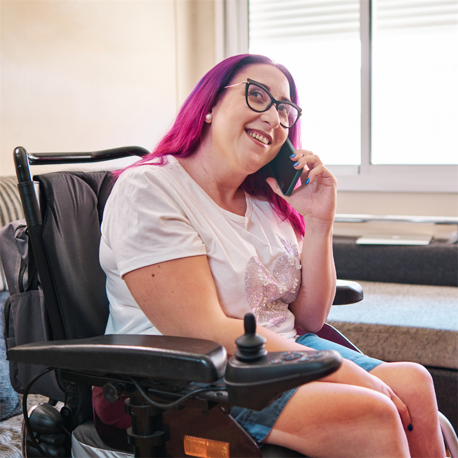woman with pink hair talking on cellphone in wheelchair