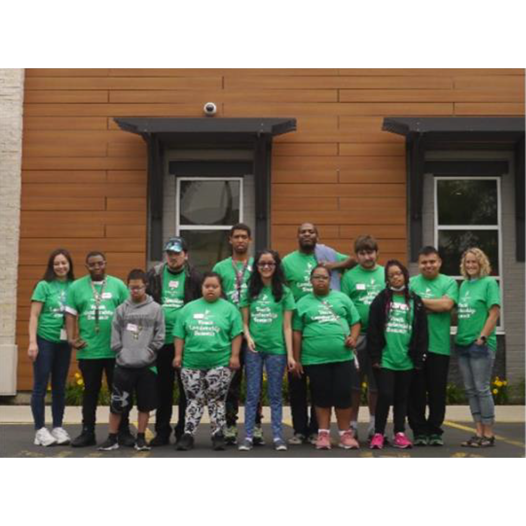 Teens smiling and wearing green Youth Leadership Summit shirts